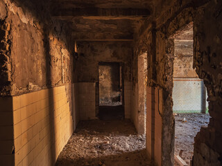 Corridor and rooms of an old ruined abandoned building with piles of rubbish and broken walls. Echoes of time