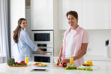 Portrait of a pretty young couple cooking salad together in kitchen lifestyle