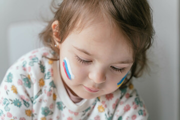 girl with the flag of russia and ukraine painted on her face claiming peace