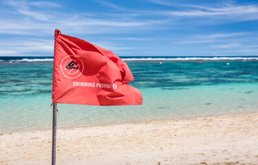 Red flag warning on sandy beach