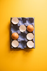 Egg shells and whole eggs in a carton. Top view.