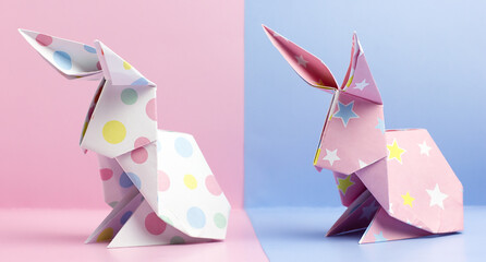 Two origami Easter bunnies on a pink and blue background