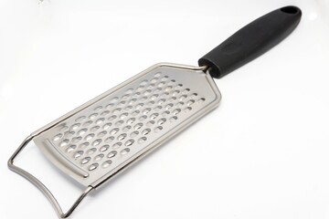 Metal grater for cheese and other kitchen ingredients on white background with copy space - Powered by Adobe