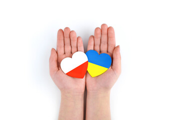 Children's hands hold two hearts with flags of Poland and Ukraine on white background. Unity...