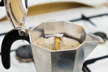 Hot freshly brewed coffee in a geyser coffee maker standing on a gas stove