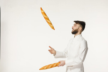 A handsome baker in uniform holds baguettes on a white background. bakery advertising concept

