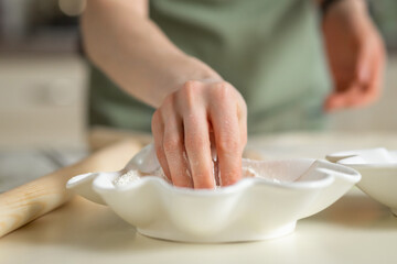 Close-up of a cook's hand taking flour from a white plate