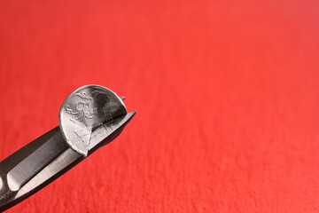 Russian ruble, scissors cut a coin with a face value of 1 Russian ruble on an orange background. The idea of the collapse of the ruble and the economy, sanctions against Russian aggression