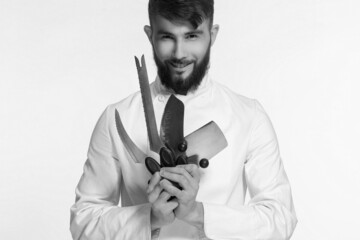 handsome chef holds a set of kitchen tools in his hands on a white isolated background. advertising concept for a restaurant or cafe