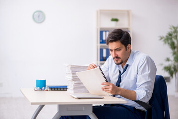 Obraz premium Young male employee and too much work in the office