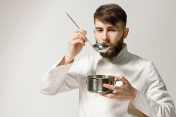 kind and handsome cook holds kitchen utensils on a white isolated background. concept for a cook