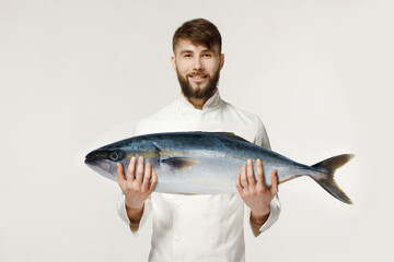 
the chef holds in his hands a big tuna on a white isolated background