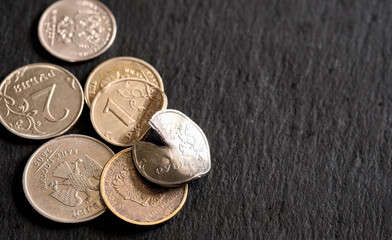 Russian coins on a black stone background, deformed and broken money. The idea of the collapse of...