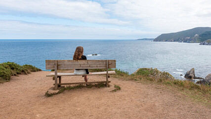 Little girl on the famous Loiba bench in Punta Estaca de Bares in Galicia, Spain