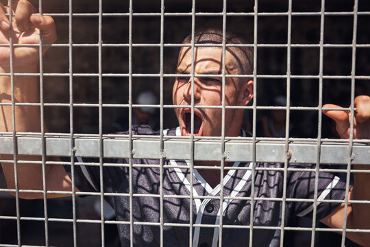 Are You A True Fan If Youre Not Slightly Obsessed. Shot Of A Young Man Watching A Game Of Baseball From Behind The Fence.