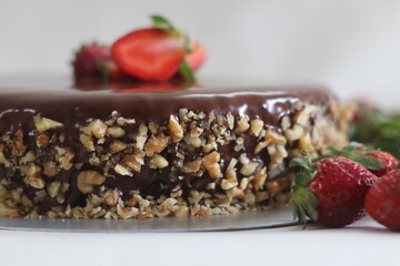 Chocolate cake with chocolate ganache and topped with walnut and fresh strawberries