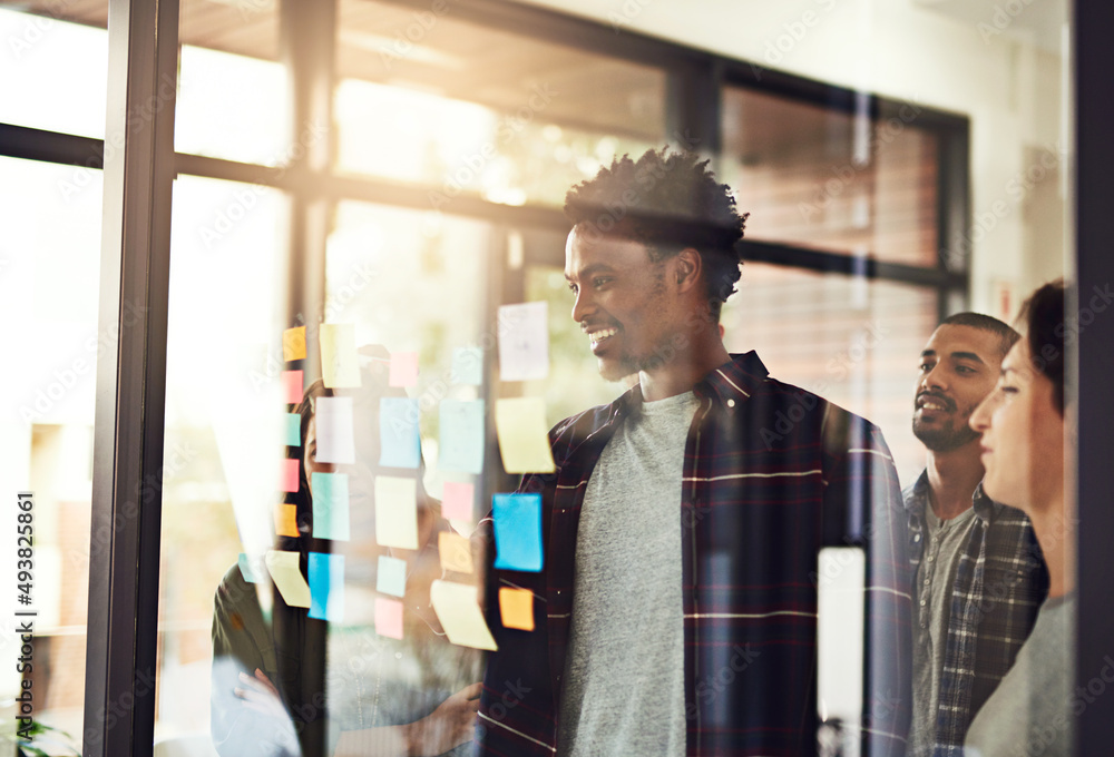 Poster it all starts with an idea. cropped shot of coworkers using sticky notes on a glass wall during an o