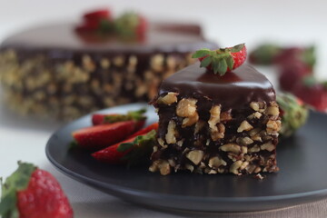 Chocolate cake slice. Chocolate cake with chocolate ganache and topped with walnut and fresh strawberries