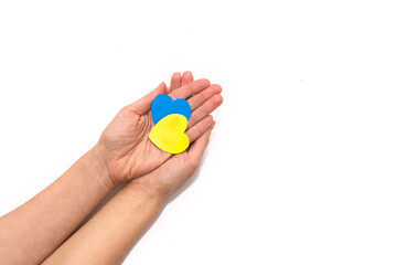 Two hearts in the colors of the flag of Ukraine in female hands. Concept of ending the war in Ukraine
