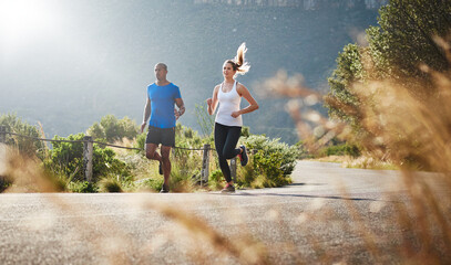 Energy and persistence conquer all things. Shot of a sporty couple out running on a mountain road.