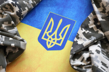 Ukrainian flag and coat of arms with fabric with texture of pixeled camouflage. Cloth with camo...