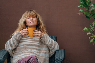 relaxed middle-aged adult woman drinking coffee on terrace