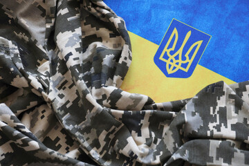 Ukrainian flag and coat of arms with fabric with texture of pixeled camouflage. Cloth with camo...