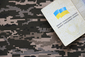 Ukrainian foreign passport on fabric with texture of military pixeled camouflage. Cloth with camo...