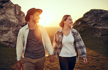 Young couple walking together in nature holding hands during sunset