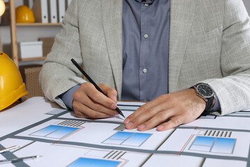 Architect working with construction drawings in office, closeup