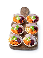 Herring salad with colorful vegetables in small tartlet isolated on white
