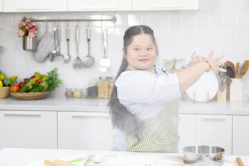 young teenage girl throwing and sprinkling white flour for making a bread or cooking food in a kitchen