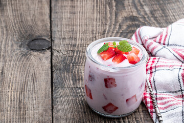 Homemade strawberry yogurt with fresh sliced berries on wooden table