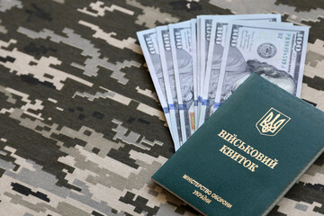 Ukrainian military ID and US dollar bills on fabric with texture of pixeled camouflage. Cloth with...