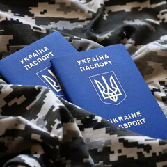 Ukrainian foreign passport on fabric with texture of military pixeled camouflage. Cloth with camo...