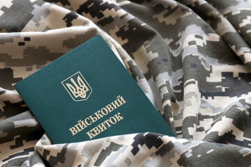 Ukrainian military ID on fabric with texture of pixeled camouflage. Cloth with camo pattern in...