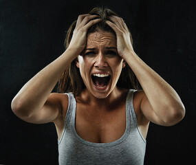 Make it go away. A young woman screaming uncontrollably while isolated on a black background.