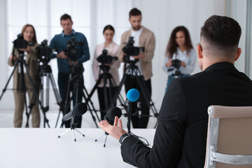 Businessman giving interview to journalists at official event, back view