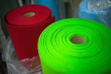 Round packages with felt fabric in production. Sale of fabric in stock. Green and red packages with...