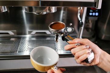 Barista prepares americano using a coffee machine.