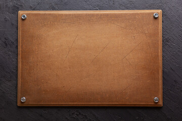Obraz premium Wooden nameplate or sign board screwed on wall background. Front view of name plate