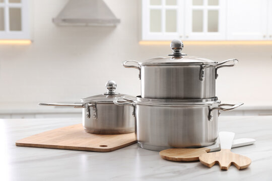 Set Of Stainless Steel Cookware And Kitchen Utensils On White Table Indoors