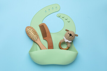 Baby accessories and bib on light blue background, top view