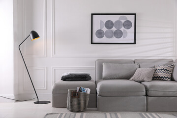 Cozy living room interior with comfortable grey sofa and beautiful picture