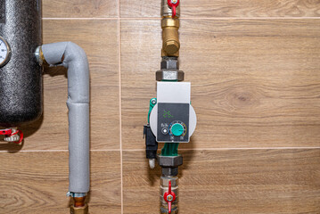 Water circulation pump for underfloor heating in a modern gas boiler room lined with ceramic tiles,...
