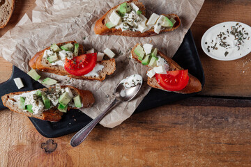 Sandwiches with pasta,avocado, tomato. Whole grain bread. Vegan sandwich from vegetables on black cutting board. Wooden background
