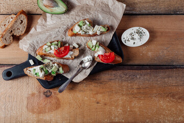 Sandwiches with pasta,avocado, tomato. Whole grain bread. Vegan sandwich from vegetables on black cutting board. Wooden background