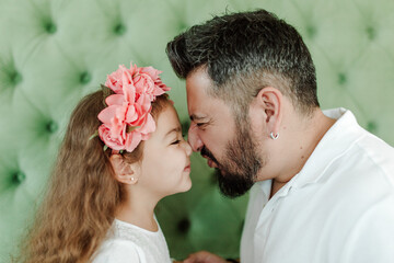 Happy hispanic dad and daughter. Green background, studio shot. Fatherhood and  father day concept