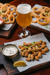 Beer set appetizers fried onion rings, squid rings and fried mussels with tartar sauce and glasses of beer