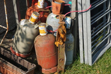 Alte ausgediente Gasflaschen im Sonnenlicht auf Wiese 